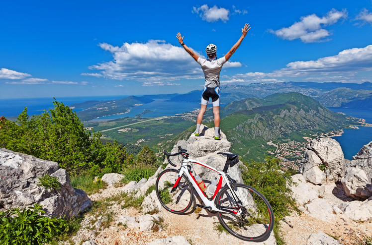 Cyclist on the top of a hill with their hands up